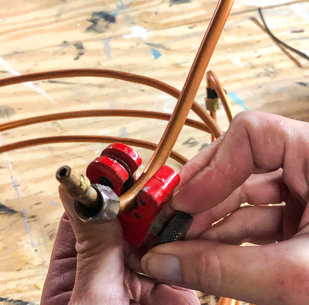 Using a pipe cutter to cut a piece of copper refrigerator water line