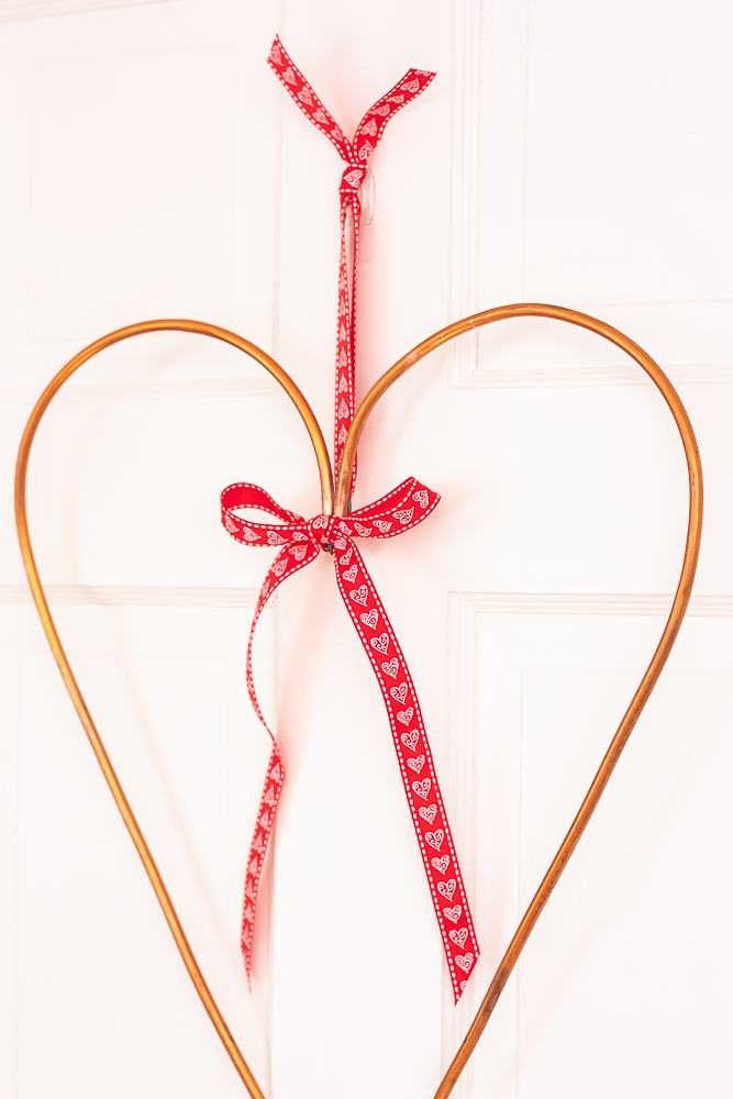 Valentine's Day wreath made from 1/4" copper pipe decorated with a red ribbon with white hearts