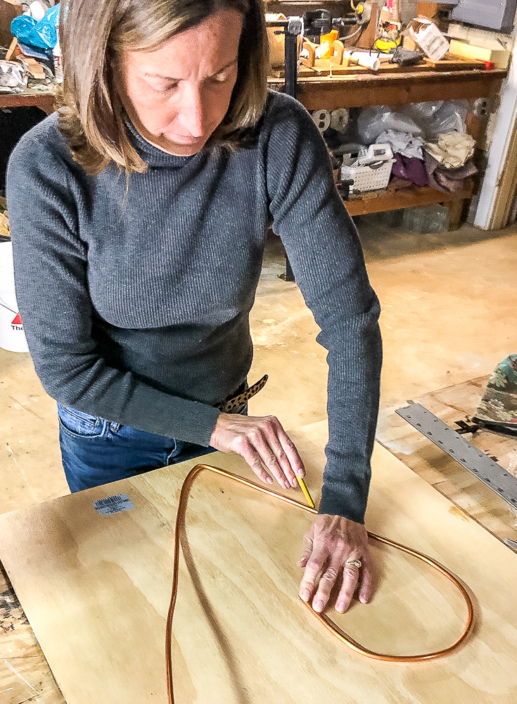 Tracing half of a heart on a scrap piece of plyboard