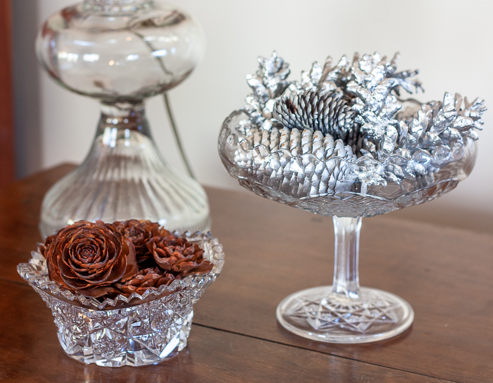 Deodar Cedar cones in a cut glass bowl with a glass compote filled with pine cones painted with silver paint