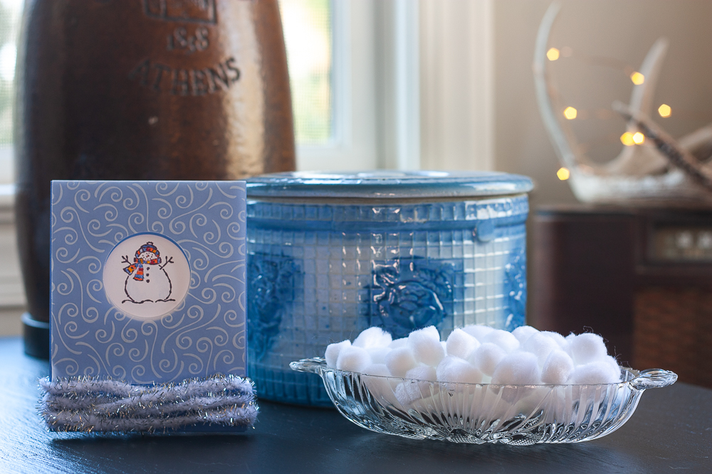 Stamped snowman card, antique blue crock, white pom-poms in a glass bowl