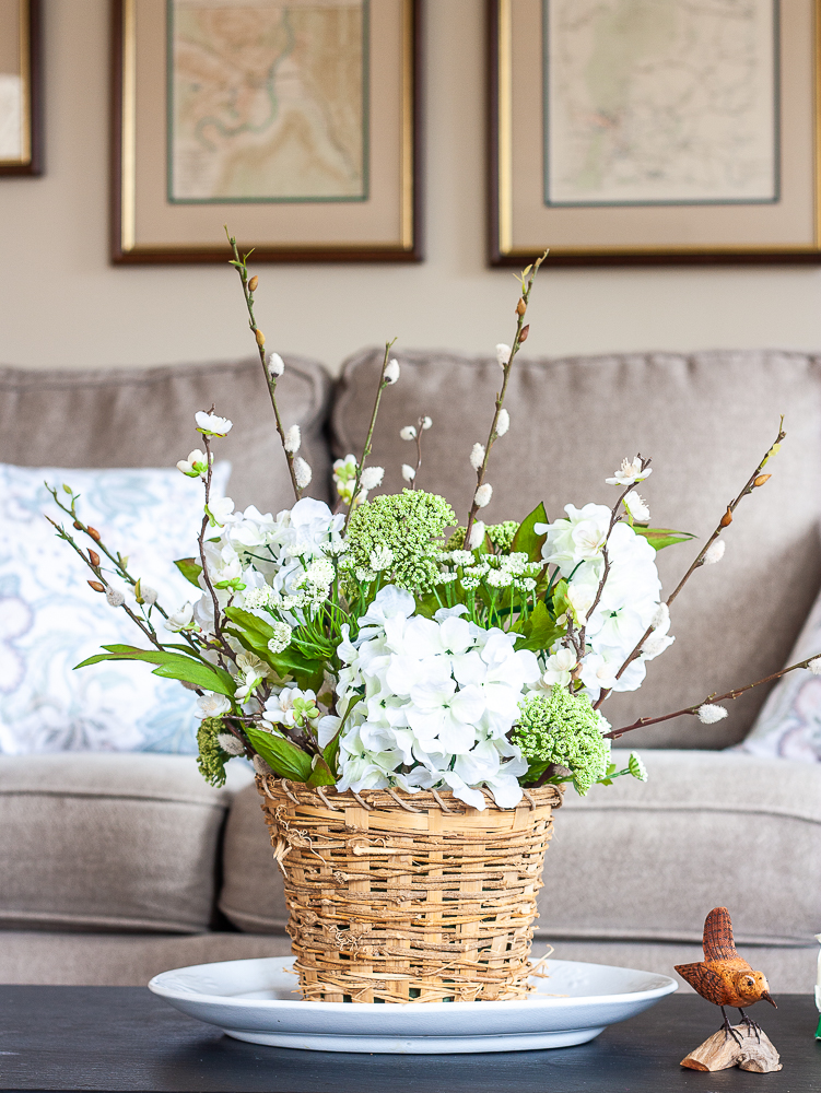 Spring flower arrangement in a woven basket on a coffee table