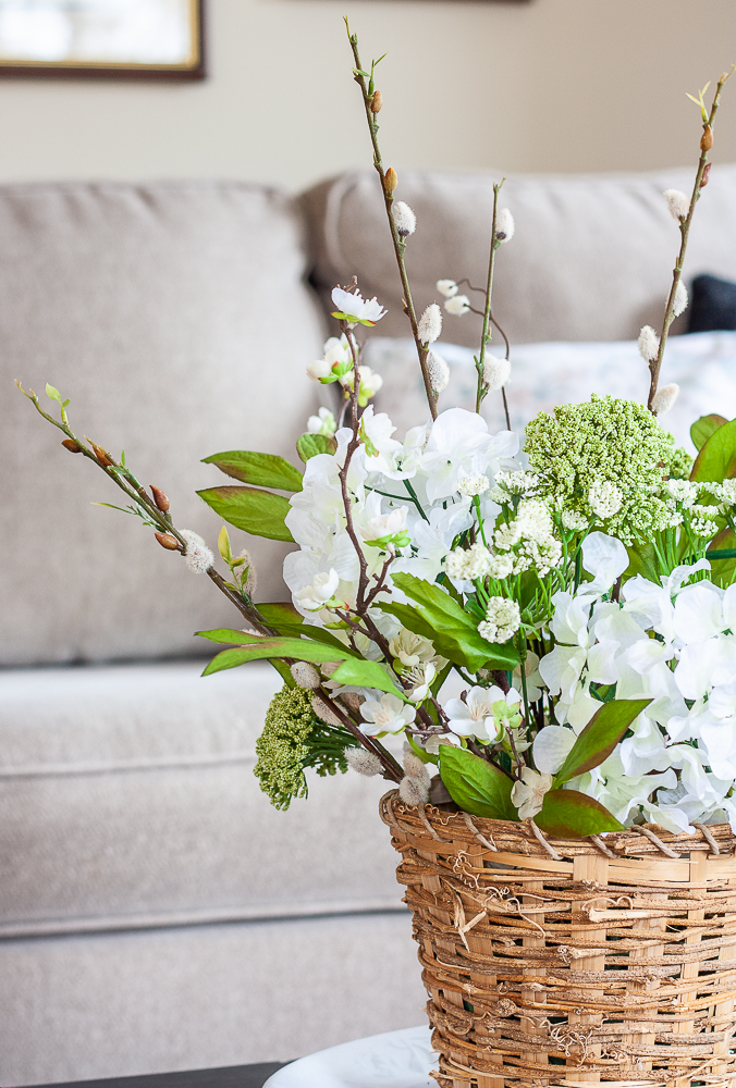 Spring flower arrangement with faux hydrangea, pussy willow, queen anne's lace in a woven basket