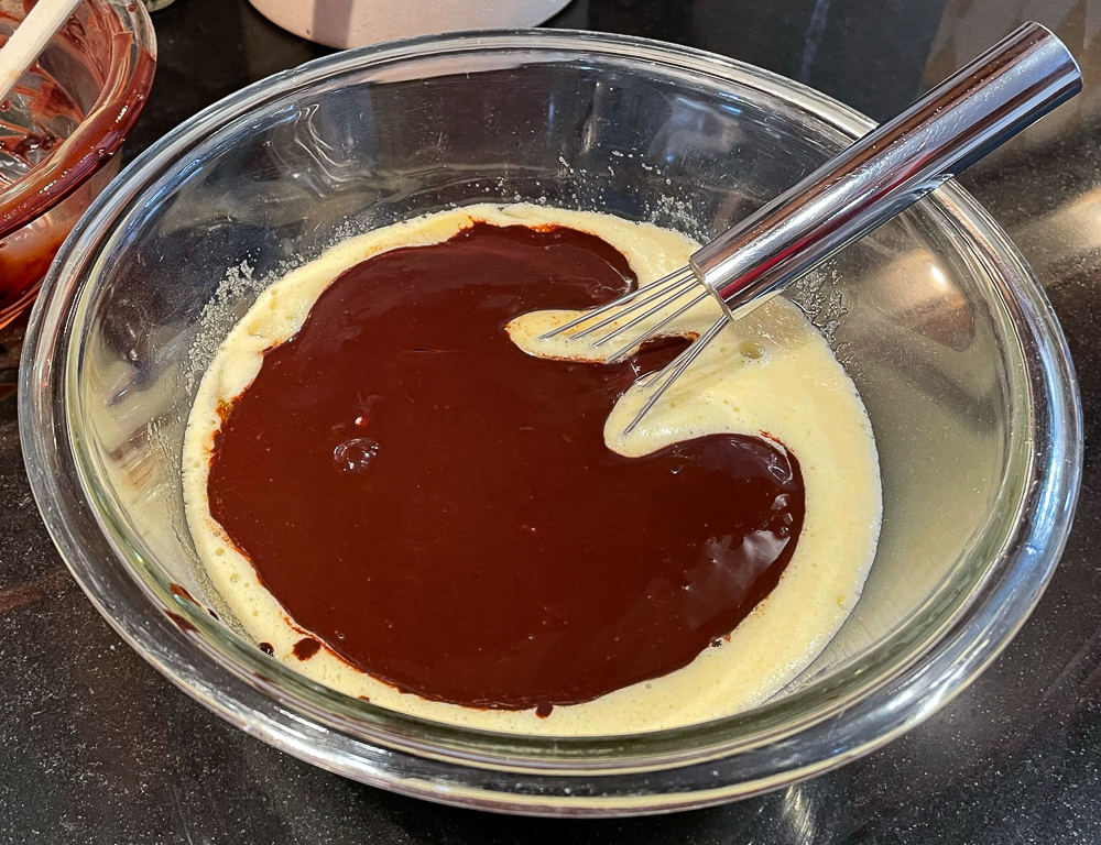 Adding melted chocolate to egg and sugar mixture when making brownies