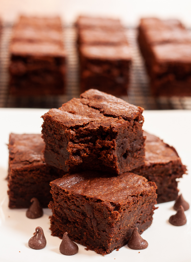 Stack of homemade brownies with brownies on a cooling rack in the background