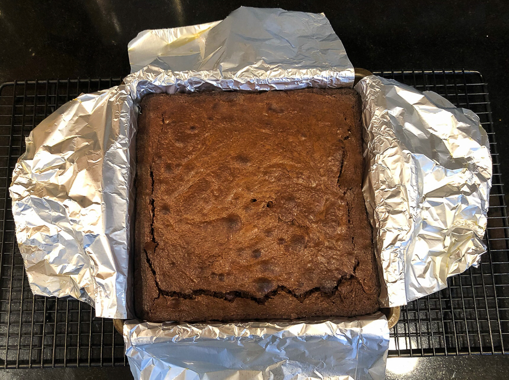 Baked brownies in a pan lined with aluminum foil