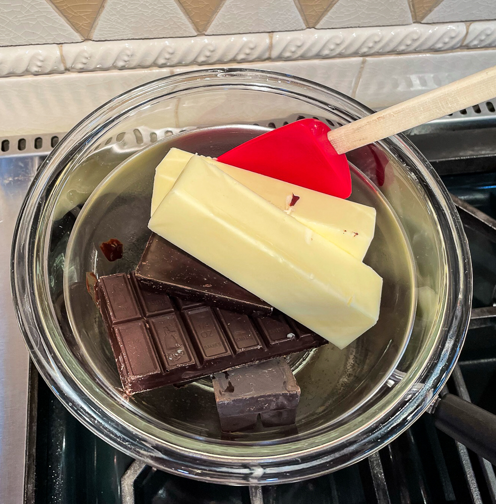 Melting two kinds of chocolate and butter in a glass bowl over simmering water