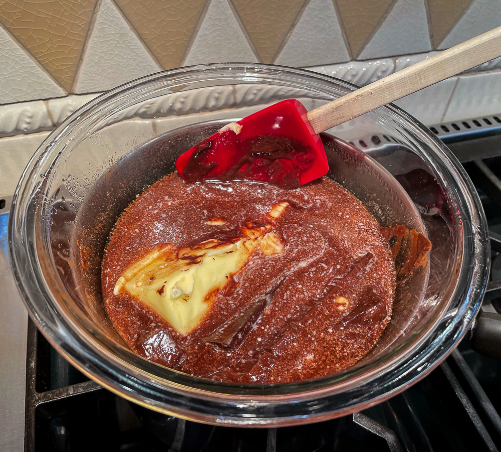 Melting two kinds of chocolate and butter in a glass bowl over simmering water