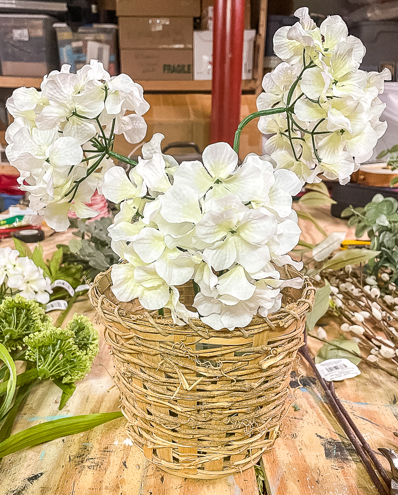 Three faux hydrangea blooms in a woven basket