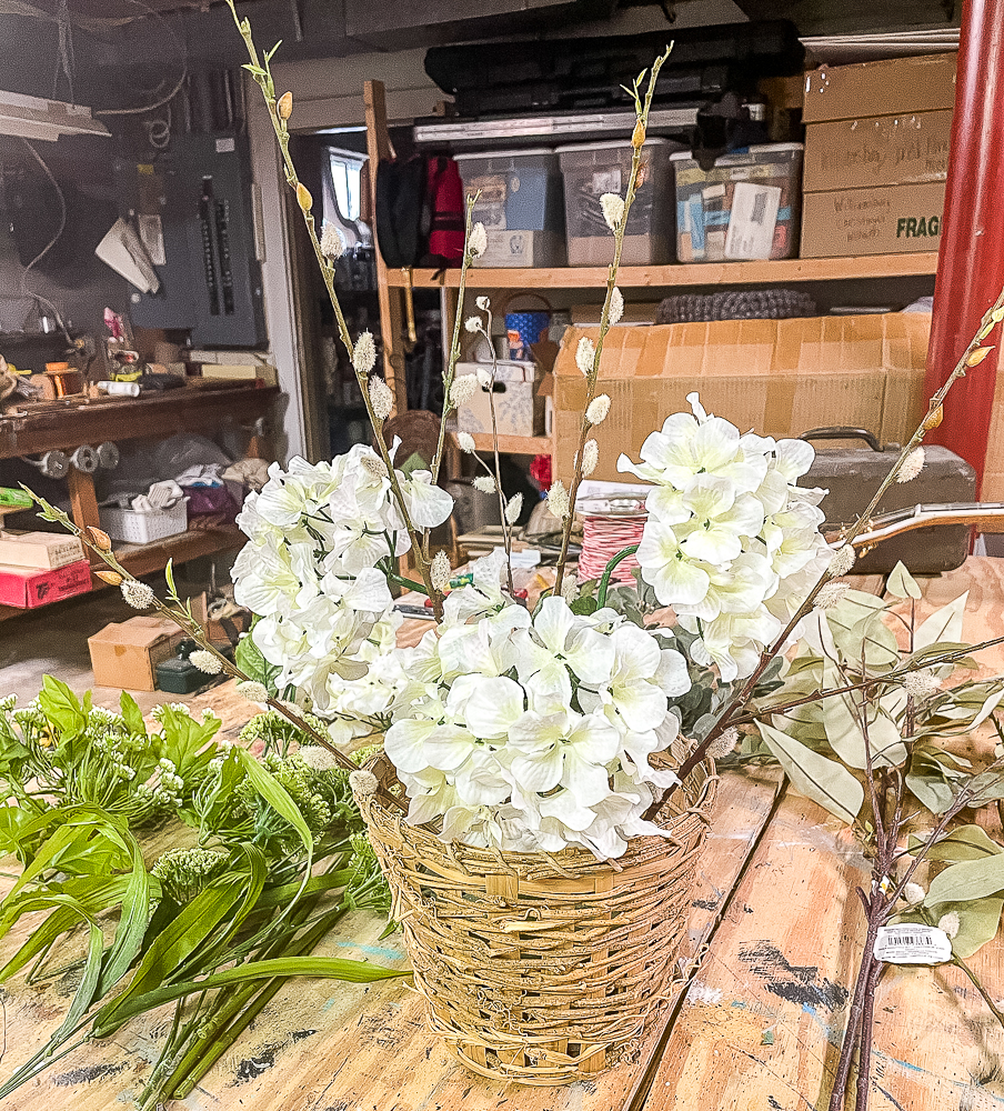 3 hydrangea blooms and pussy willow stems in a woven basket