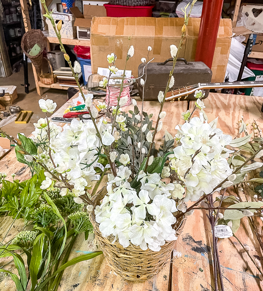 3 hydrangea blooms, pussy willow stems, and flowering apple stems in a woven basket