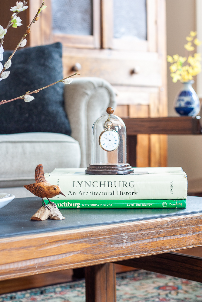 Hand-carved bird displayed with S. Allen Chambers Lynchburg an Architectural History book and Lynchburg, A Pictorial History Book and an antique pocket watch displayed on a 1960s slate topped coffee table