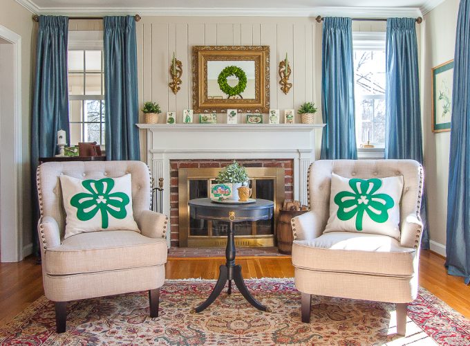 Living room decorated for St. Patrick's Day with Shamrock pillows, green and gold vignettes, green plants and wreaths, and vintage St. Patrick's Day postcards