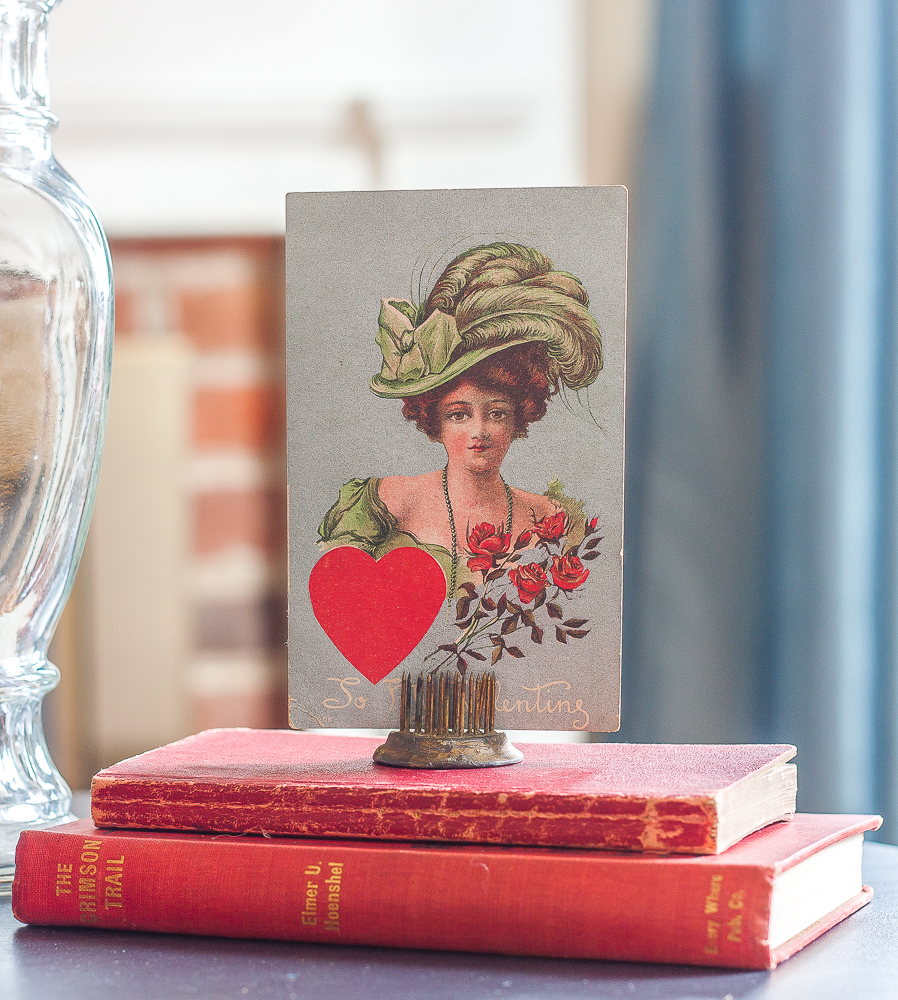 Valentine's Day vignette with vintage red books and a vintage early 1900s postcard.