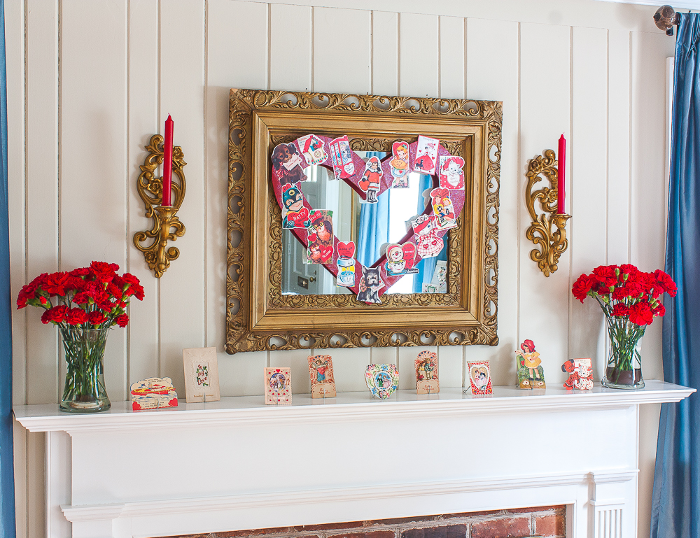 Mantel decorated for Valentine's Day with vintage Valentine's Day cards, red carnations, and red candles