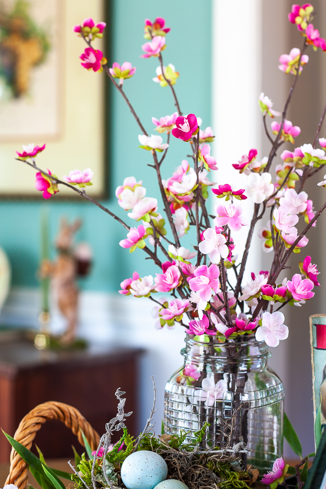 Pink faux florals in a vintage, clear, embossed Mason jar with a bird nest