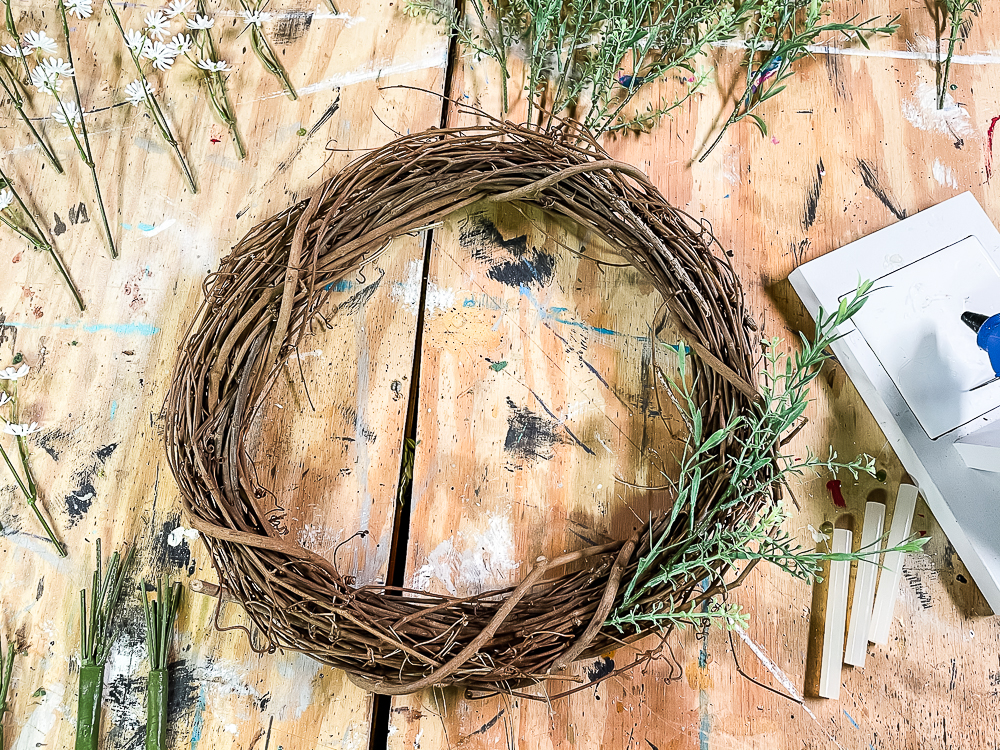 Grapevine wreath with two sprigs of faux spring greenery