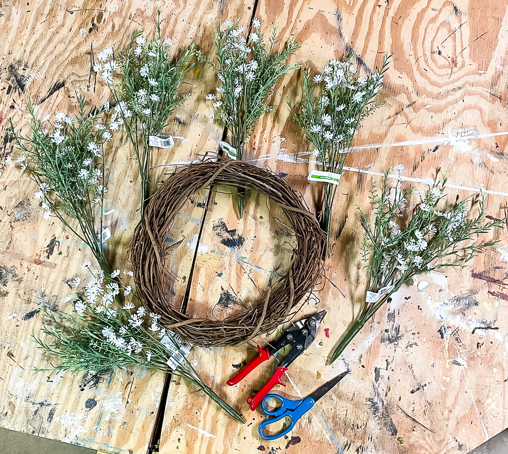 Grapevine wreath, faux florals, tin snips, scissors on a workbench