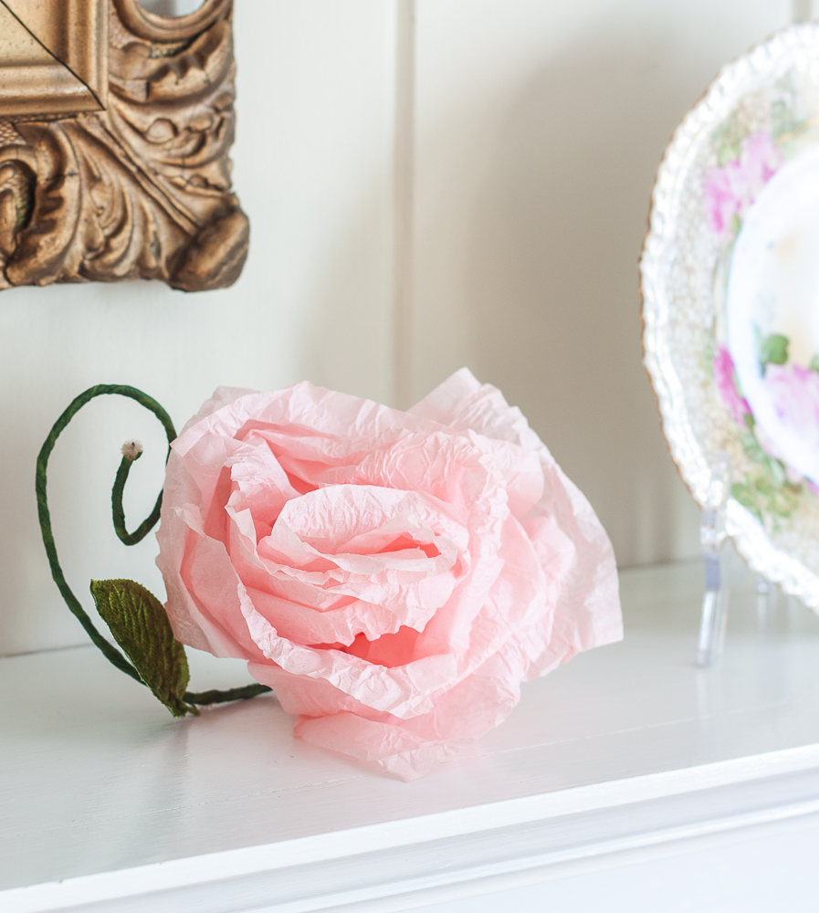 Pink crepe paper flower with a green stem and faux leaf