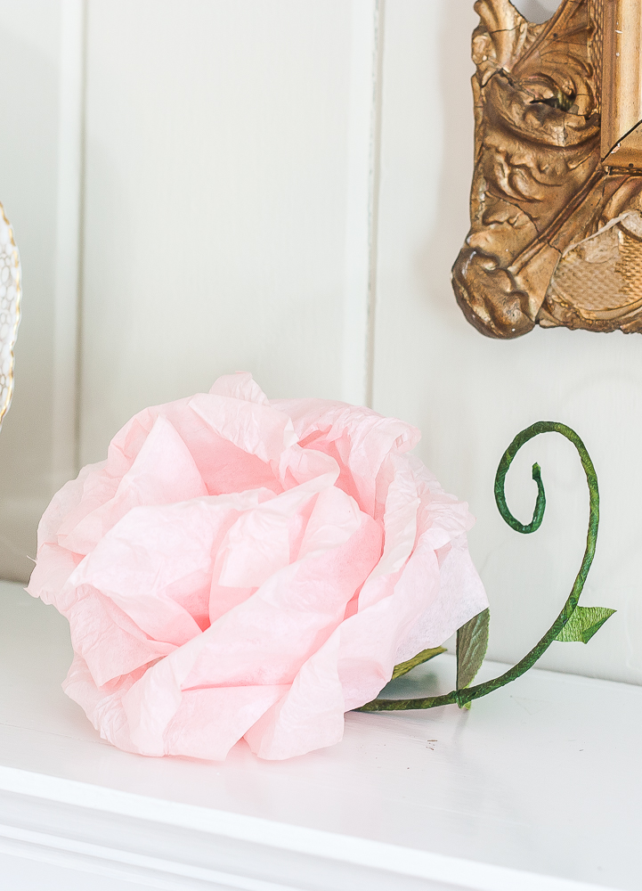 Pink crepe paper flower with a green stem and faux leaf