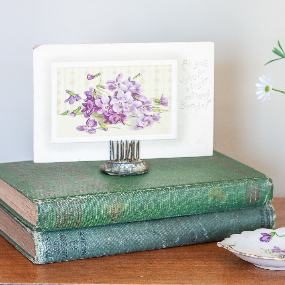 Early 1900s violet postcard displayed on top of two antique books