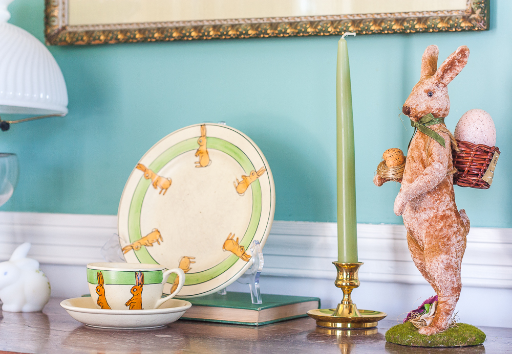 Roseville pottery 1920s juvenile rabbit cup and saucer and matching bunny plate with a Fenton glass rabbit, brass candle holder with a green candle, and a velveteen bunny