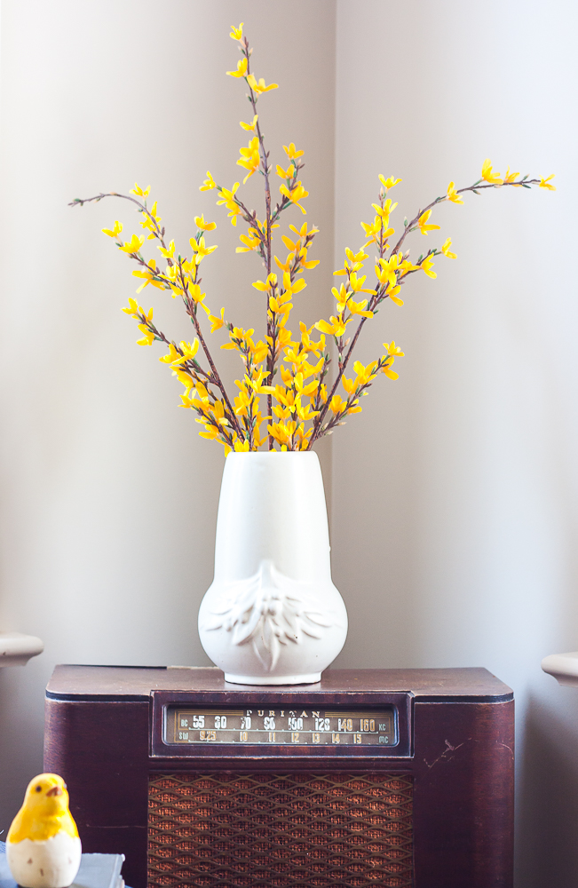 Vintage white vase filled with faux Forsythia