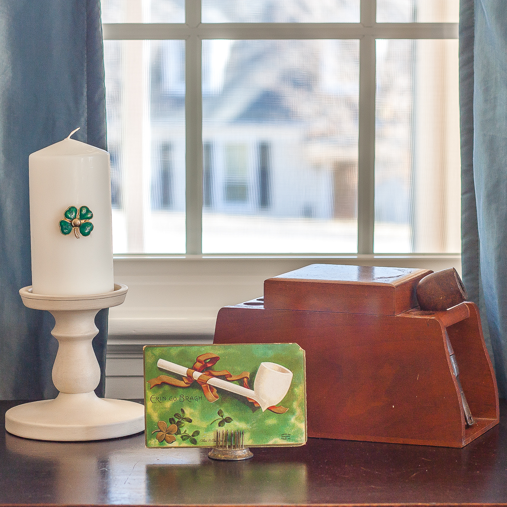 Antique St. Patrick's Day postcard, pipe and tobacco box, candle on a candle holder with a green clover pin glued to it.