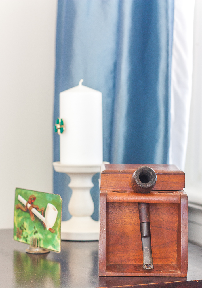 Antique St. Patrick's Day postcard, pipe and tobacco box, candle on a candle holder with a green clover pin glued to it.