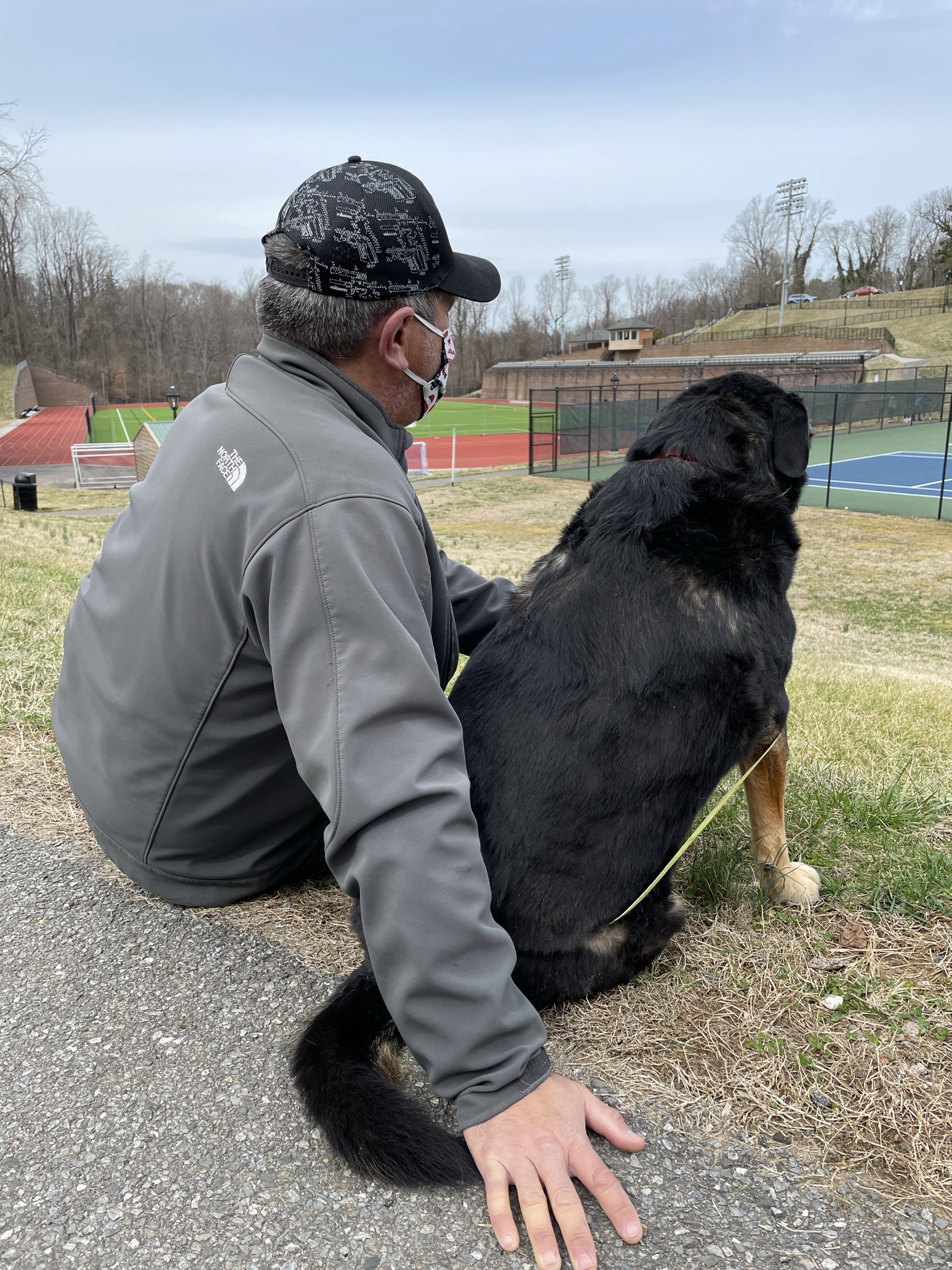 Man and dog watching tennis at Randolph College in Lynchburg, VA