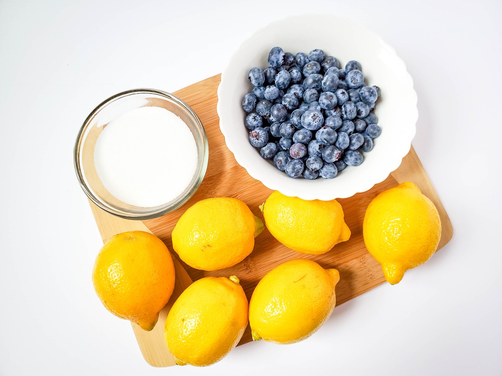 Sugar, blueberries, lemons on a wooden cutting board