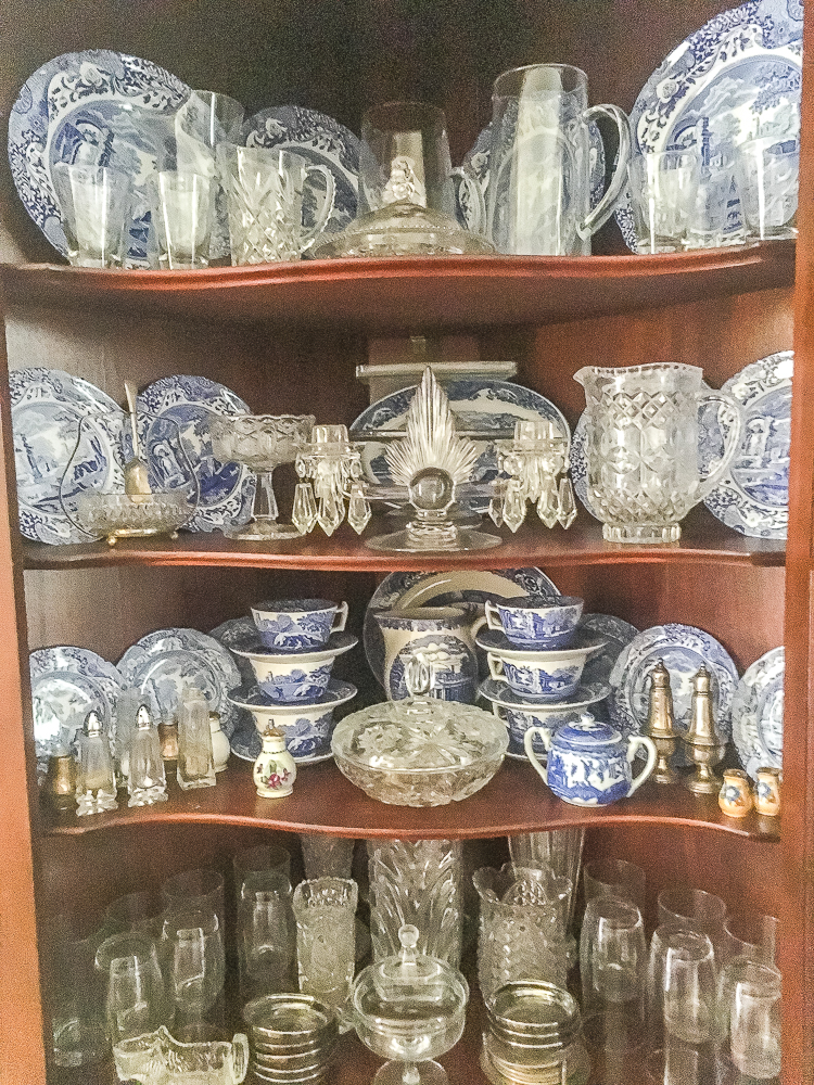 Antique corner cabinet decorated with blue and white china and glassware