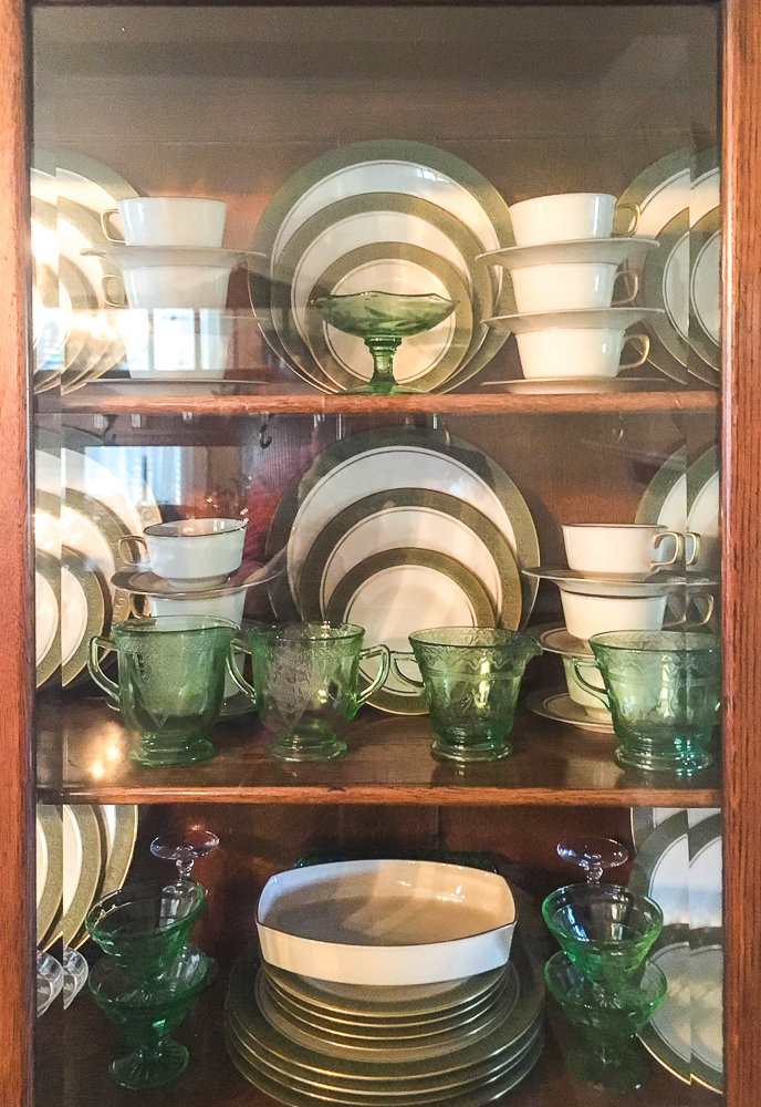 Antique oak china cabinet filled with green depression glass, 1968 china and crystal, and silver