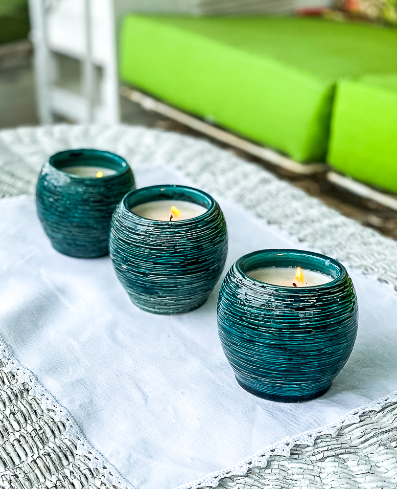 Three homemade Citronella candles on a wicker coffee table on a porch