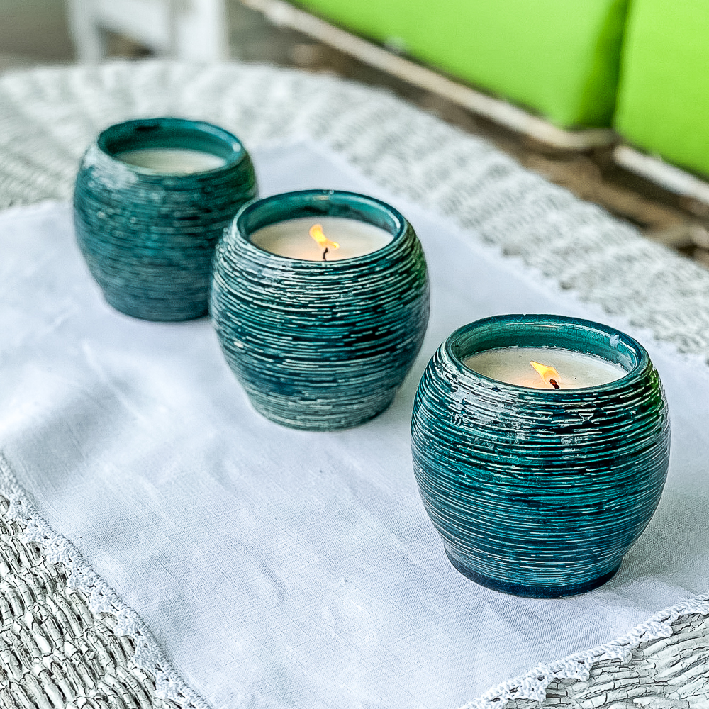 Three homemade Citronella candles on a wicker coffee table