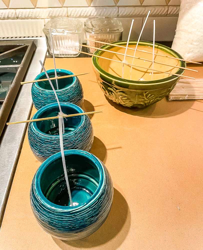 Candle wicks in a group of empty candle containers