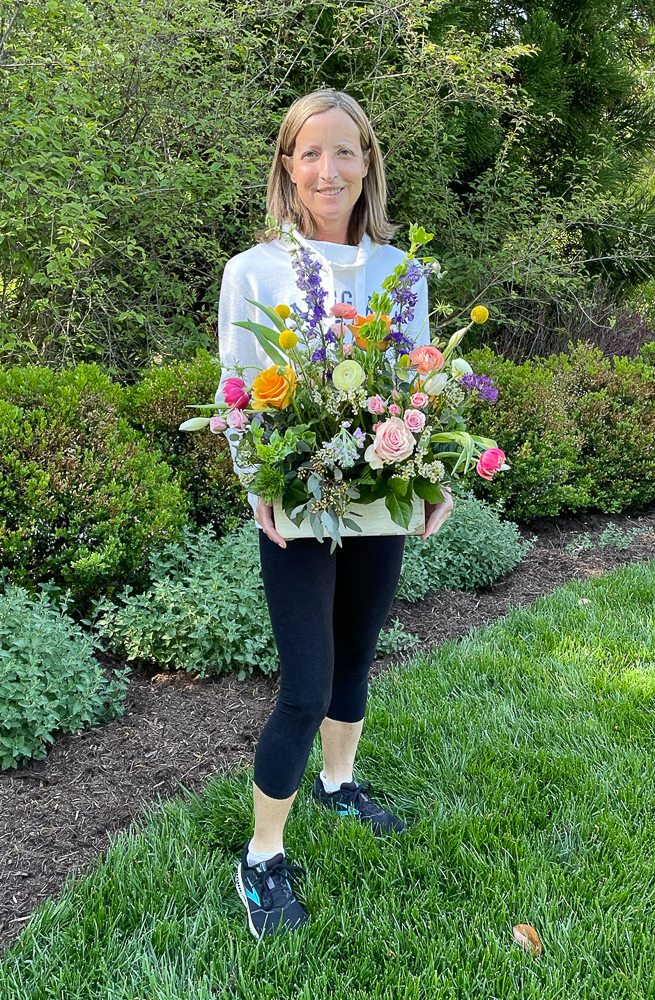 Woman holding a spring arrangement in a wooden box from a florist