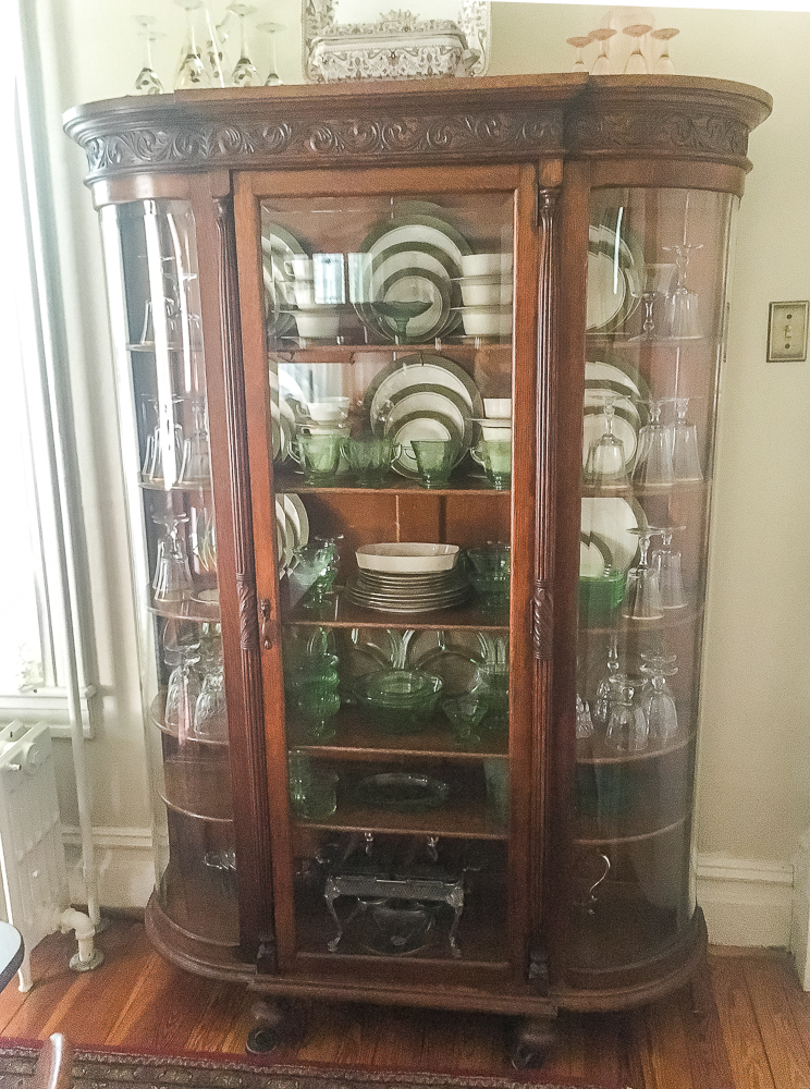 Antique oak china cabinet filled with green depression glass, 1968 china and crystal, and silver