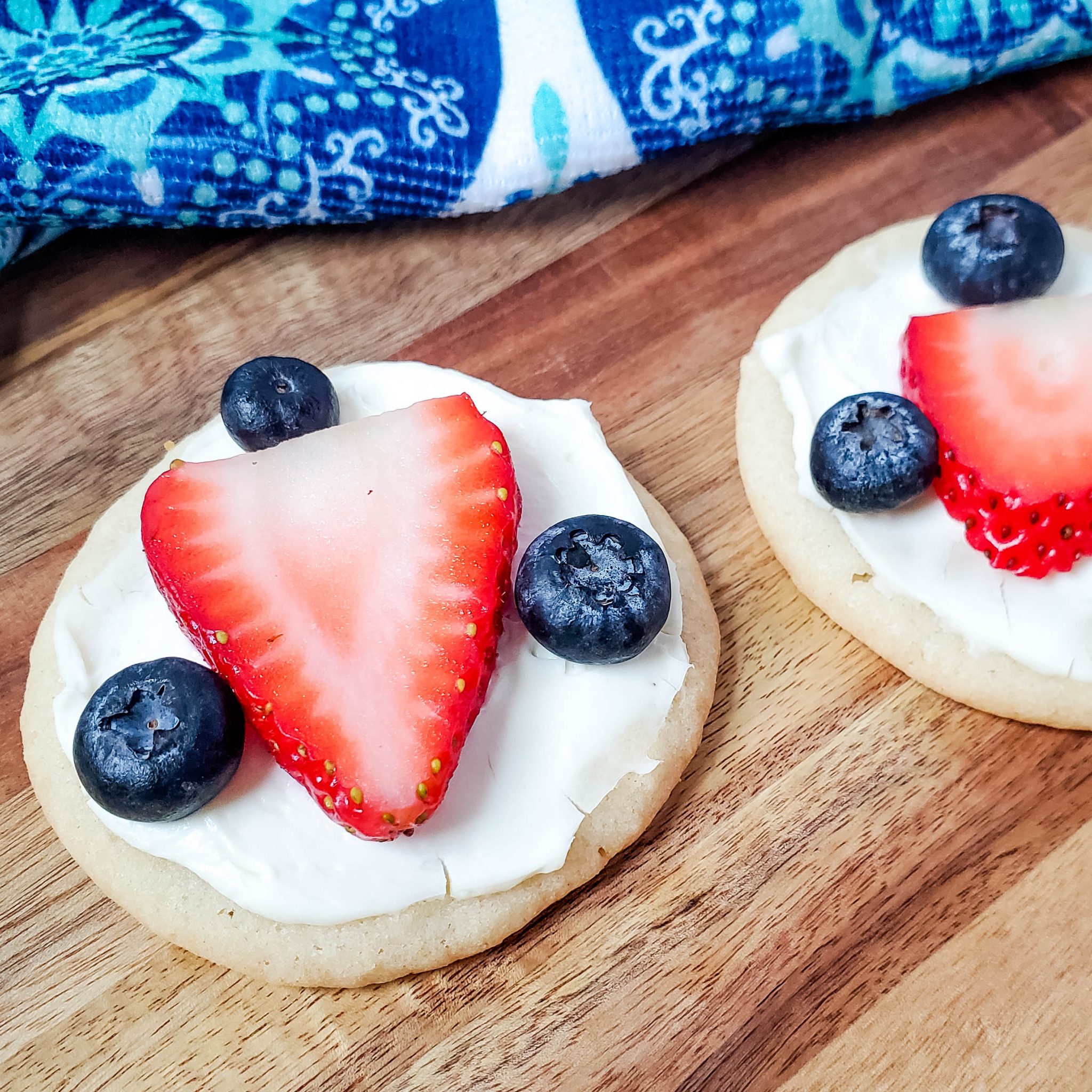 Sugar cookie with cream cheese frosting decorated with a strawberry and three blueberries