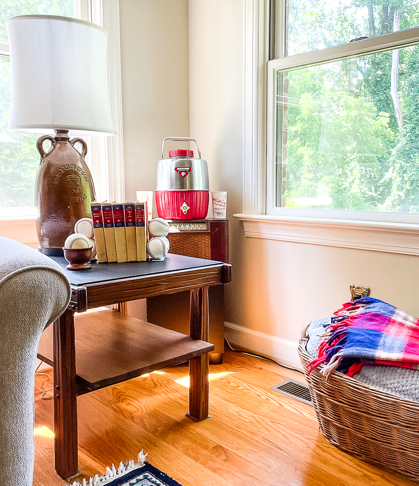 Living room corner decorated with a vintage thermos, baseballs, and Zane Gray books