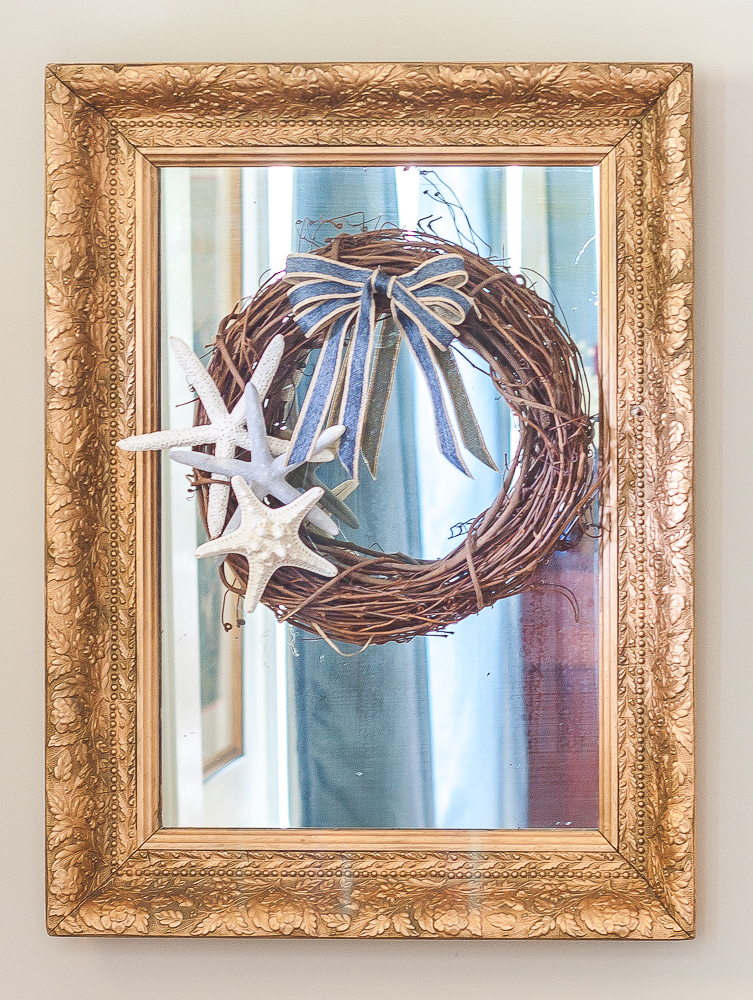 Antique mirror with a gold frame with a wreath decorated in a coastal style