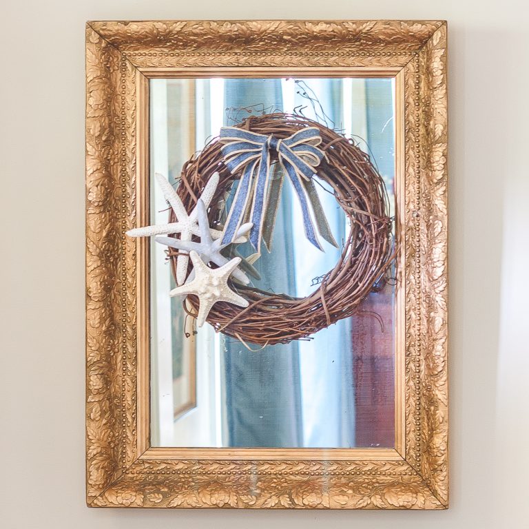 Antique mirror with a gold frame with a wreath decorated in a coastal style