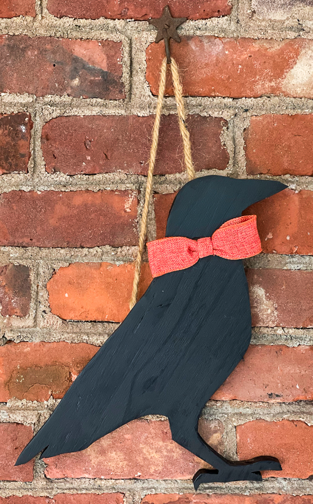 Fall wood cutout crow with an orange ribbon hanging by twine