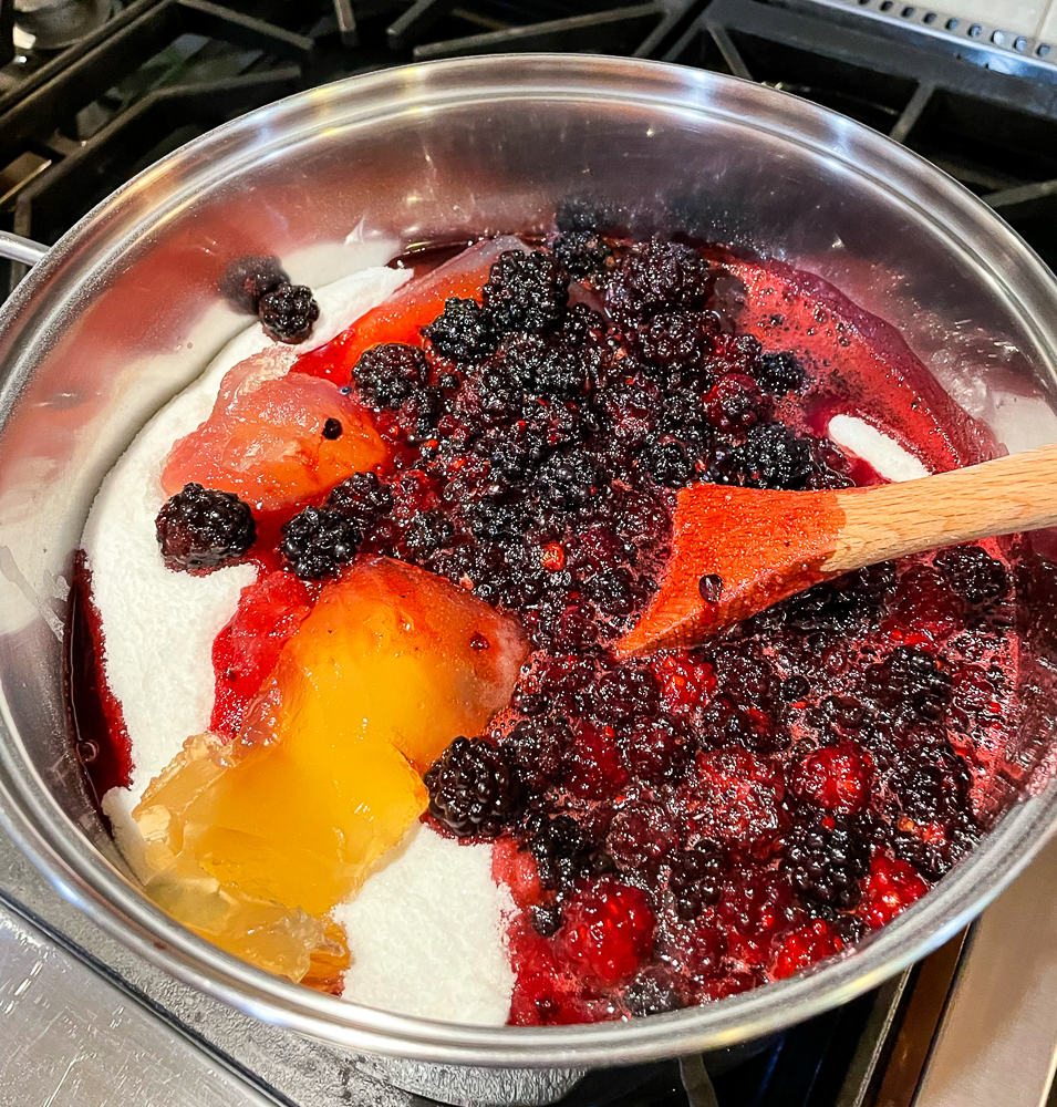 Blackberries, sugar, and pectin in a pot on a stove