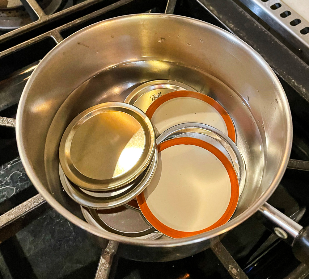 canning lids warming in a saucepan