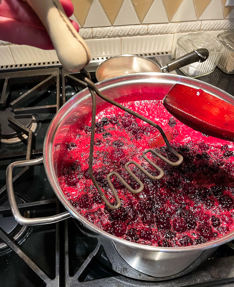 Using a potato masher to crush blackberries