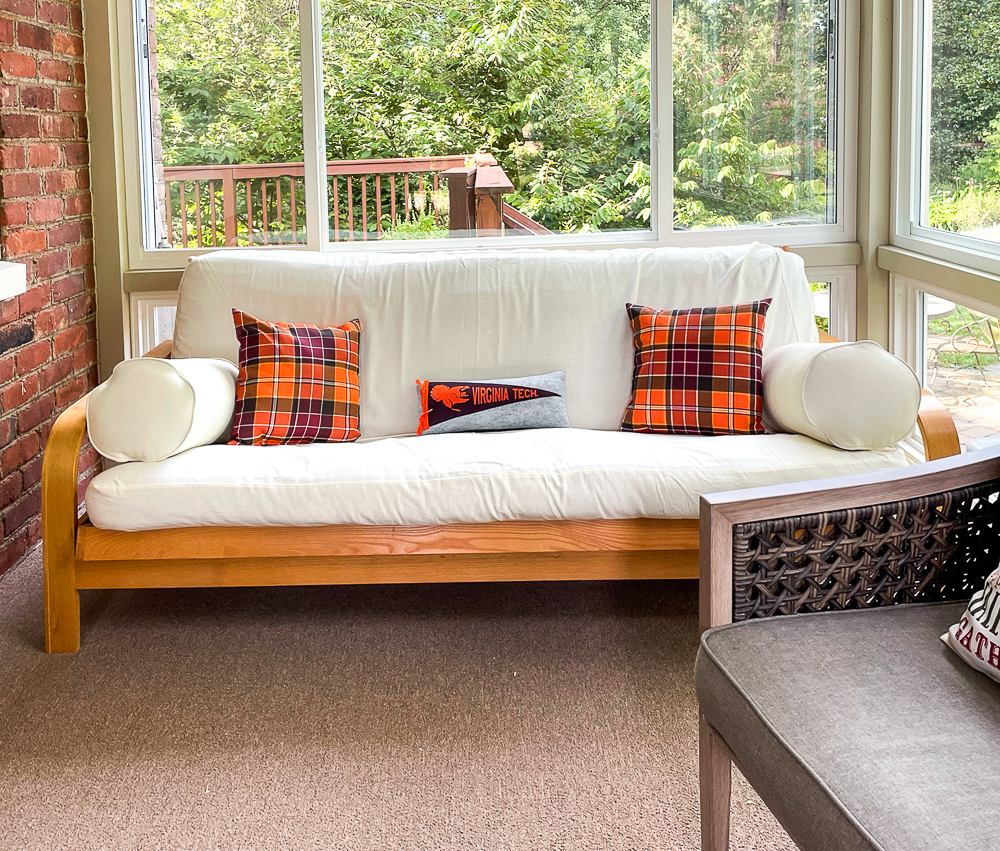 Futon in a sunroom with fall plaid pillows