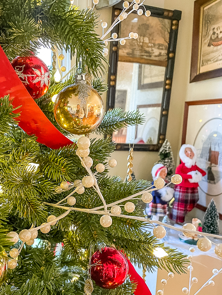 Christmas tree decorated with red ribbon, gold and red balls, and white berries