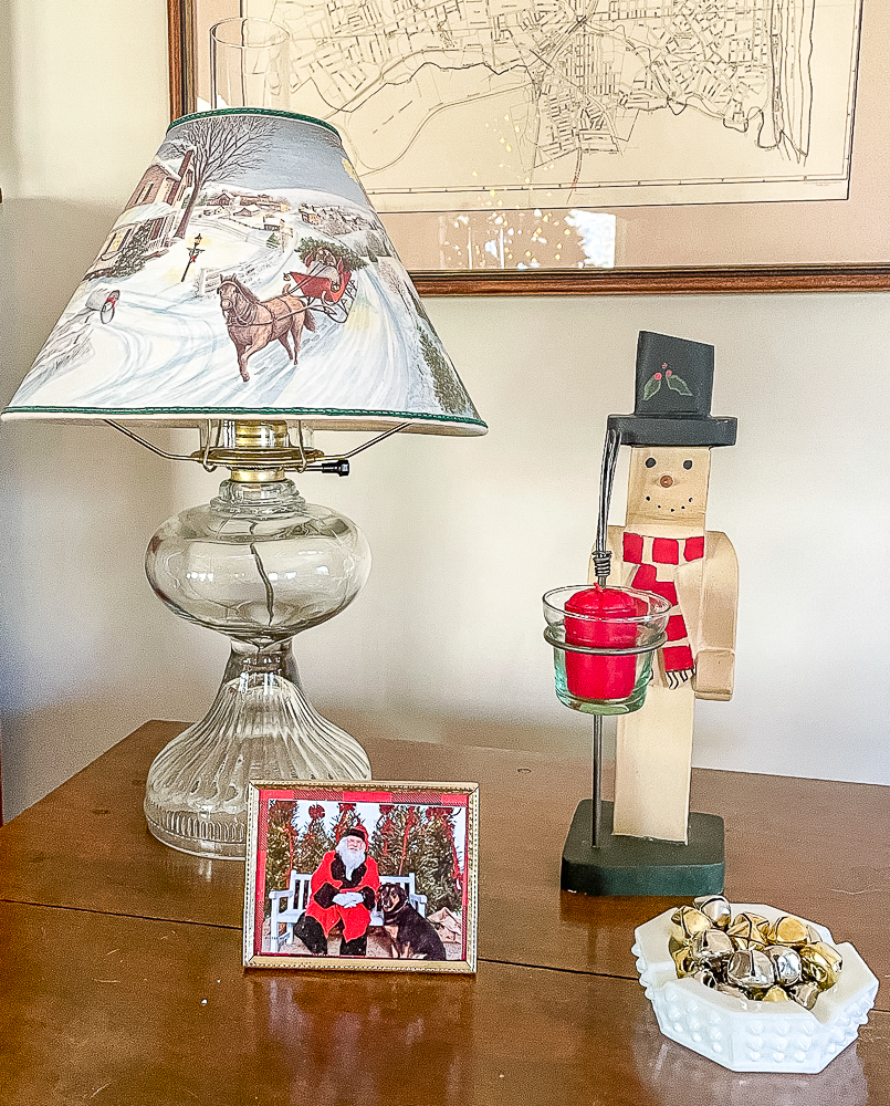 Christmas paper lampshade, snowman, dog with Santa, and a hobnob ashtray filled with jingle bells