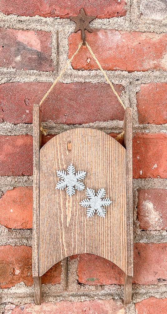 Handmade wooden sled hanging on a brick wall